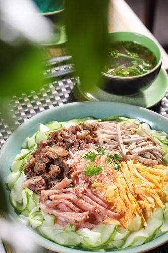 a plate of food with meat and vegetables on a table at ÊMM Hotel Hue in Hue