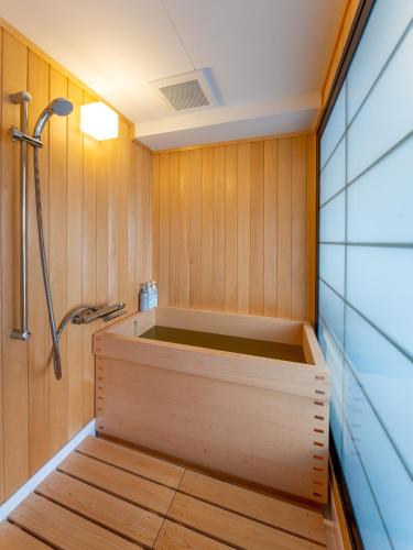 a sauna with a shower and a wooden wall at Wanosato Kyoto Musee in Kyoto