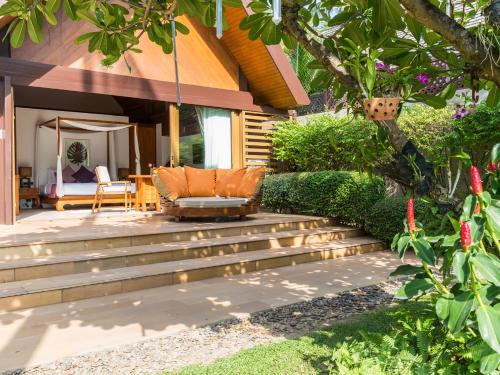 a patio with a couch on the stairs of a house at Baan Puri - SHA Extra Plus in Lipa Noi