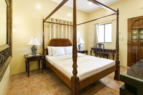 a bedroom with a four poster bed and two tables at Turtle Bay Dive Resort in Moalboal