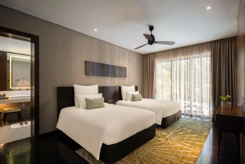 a hotel room with two beds and a mirror at Mangala Estate Boutique Resort - Small Luxury Hotels of the World in Kuantan