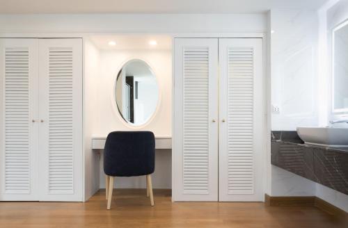 a bathroom with a black chair and a mirror at Rembrandt Hotel Bangkok in Bangkok