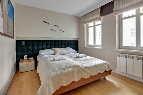 a bedroom with a bed and two windows at Willa Morska Deluxe by Grand Apartments in Sopot