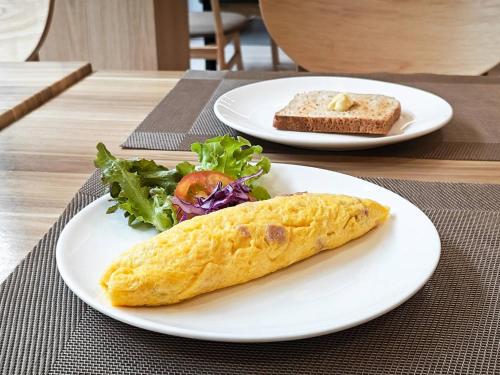 a plate with a burrito and a salad on a table at Hi Chiangrai Hotel in Chiang Rai