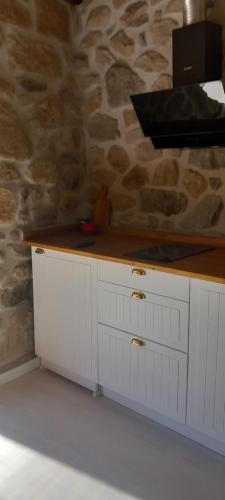 a kitchen with white cabinets and a stone wall at Casa de silvares - Rústica in Celorico de Basto