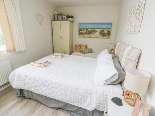 Un dormitorio con una cama blanca y una mesa. en Sunset Sands, en Conwy