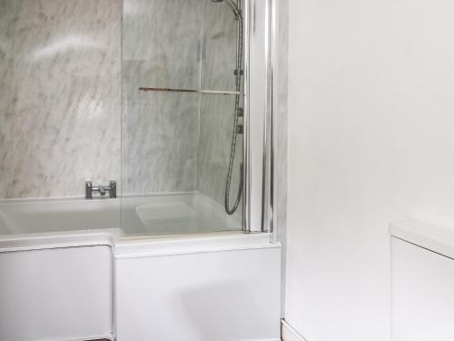 a white bathroom with a shower and a sink at Panteg Cottage, Newport in Newport Pembrokeshire
