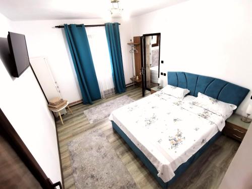 a bedroom with a bed and blue curtains at Pensiunea Fira in Baia de Fier