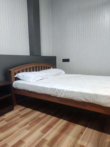 a bedroom with a bed with white sheets and a wooden floor at Vidhara Rooms in Trivandrum