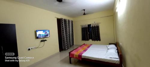 a bedroom with a bed and a tv in it at Vidhara Rooms in Trivandrum