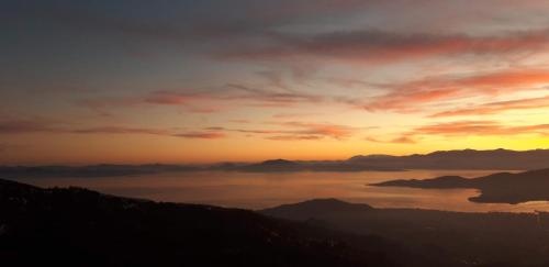 a sunset over a body of water with mountains at Μακρινίτσα Αλώνια in Makrinítsa