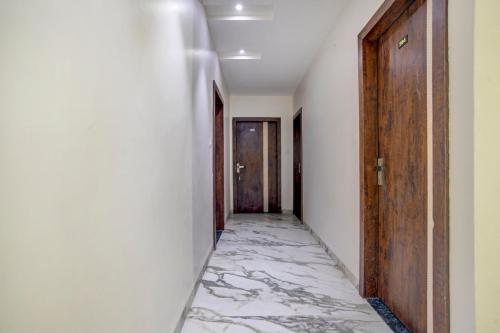 a hallway with a marble floor and wooden doors at Capital O Abri Krishna in Indore