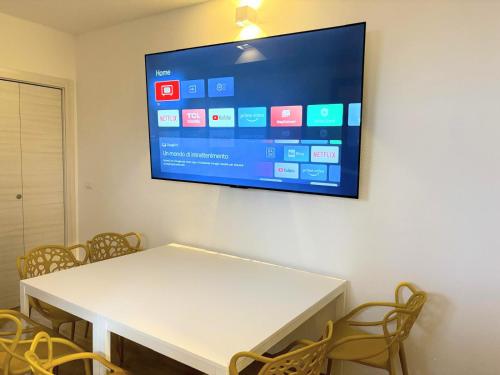 a table with chairs and a tv on a wall at La Grotta 2 Bedrooms in Urzulei