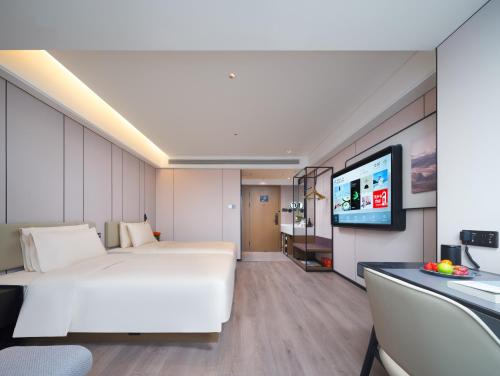 a bedroom with a white bed and a flat screen tv at Atour Hotel Zhengzhou Erqi Plaza David City in Zhengzhou