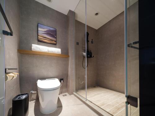 a bathroom with a toilet and a glass shower at Atour Hotel Zhengzhou Erqi Plaza David City in Zhengzhou