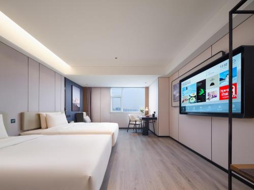 a hotel room with two beds and a flat screen tv at Atour Hotel Zhengzhou Erqi Plaza David City in Zhengzhou