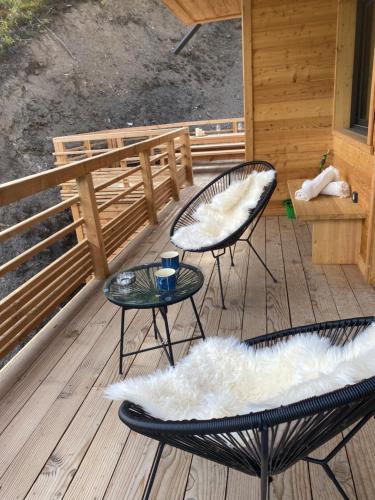 two chairs and a table on a deck at Un Écrin de Sérénité Face aux Montagne chalet nathalya in Vars
