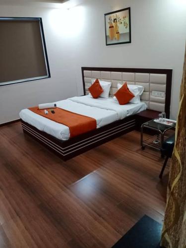 a bedroom with a large bed with orange pillows at Hotel Raviraj Palace in Rajkot