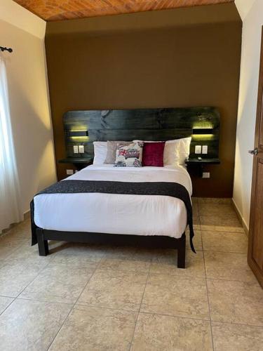 a bedroom with a large bed with a wooden headboard at Casa Vallejo in San Miguel de Allende