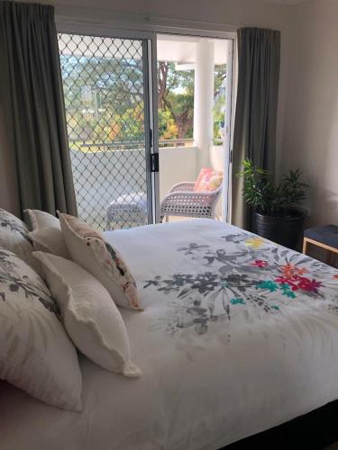 a bedroom with a bed with pillows and a balcony at Alroy Street 4/7 in Aitkenvale