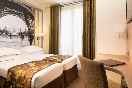 a hotel room with two beds and a desk with a laptop at Turenne Le Marais in Paris