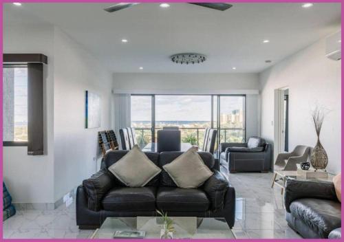 a living room with a leather couch and a table at Luxe On Duke in Stuart Park