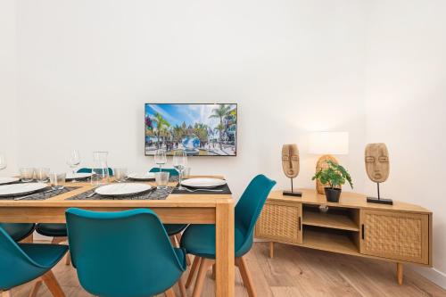 une salle à manger avec une table en bois et des chaises bleues dans l'établissement Maison abba trois pièces, à Saint-Antoine