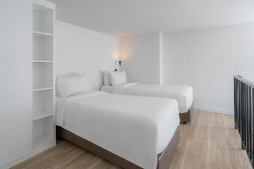 two beds in a bedroom with white walls and wooden floors at SureStay by Best Western Bangkok Ramintra in Bangkok