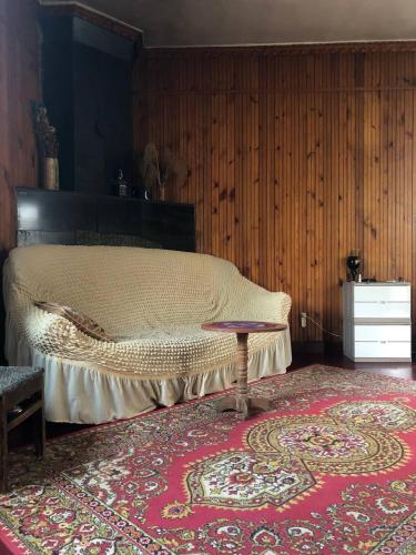 een slaapkamer met een bed met een tapijt en een tafel bij Дом Бобоквати in Kobuleti