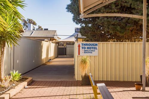 a sign on a fence next to a driveway to a house at The Sundowner Cabin & Tourist Park in Whyalla