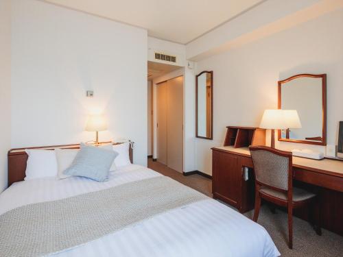 a hotel room with a bed and a desk and a mirror at Gran Palette Hakodate in Hakodate