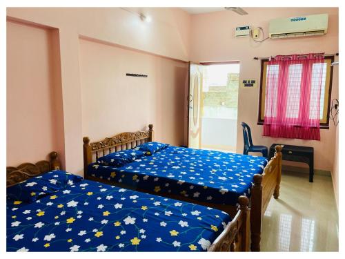 a bedroom with two beds with blue sheets and a window at THIRUNALLAR S A RESIDENCY in Thirunallar
