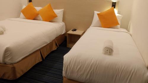 two beds in a hotel room with orange pillows at hotel bintang in Kuala Lumpur