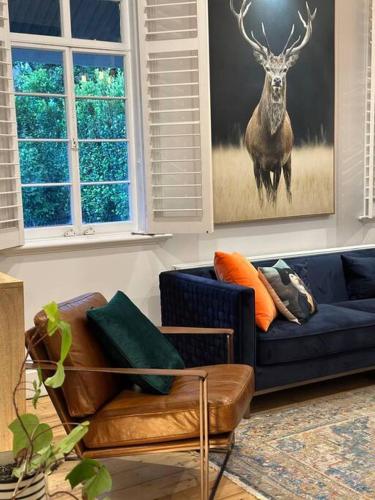 a living room with a blue couch and a deer painting at Gable House in Geelong