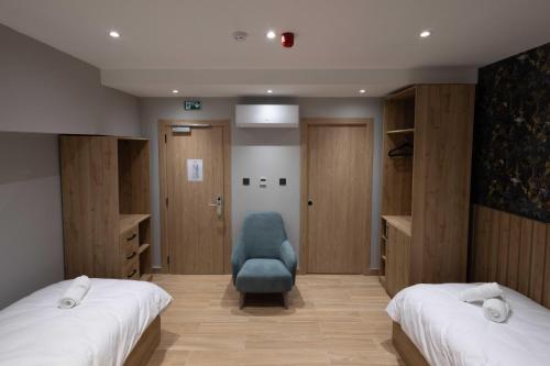 a bedroom with two beds and a blue chair at University Boutique Rooms in Msida