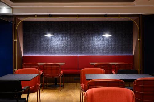 a restaurant with red chairs and tables and a wall at Olah Poshtel Taichung Wenxin in Taichung