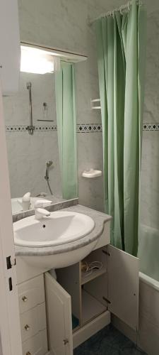 La salle de bains est pourvue d'un lavabo et d'un rideau de douche vert. dans l'établissement CAP6 Studio 4 personnes, au Cap d'Agde
