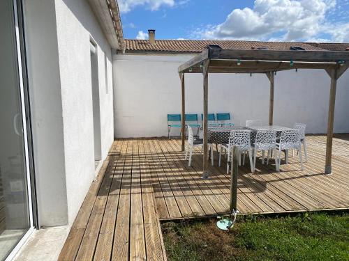 a wooden deck with a table and chairs on it at Maison Royan 9 personnes in Médis