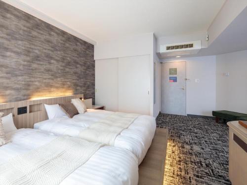 two beds in a bedroom with a brick wall at Gran Palette Hakodate in Hakodate