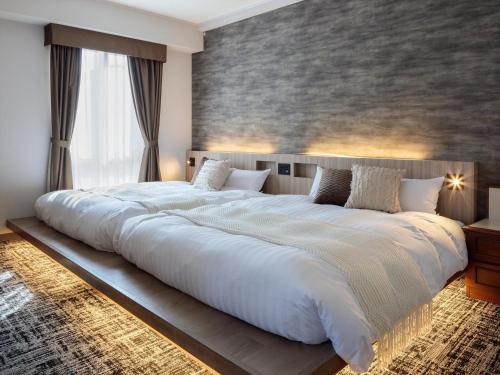 a large white bed in a bedroom with a wall at Gran Palette Hakodate in Hakodate