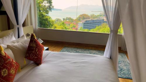 a bed in a room with a large window at Ambong Rainforest Retreat in Pantai Cenang