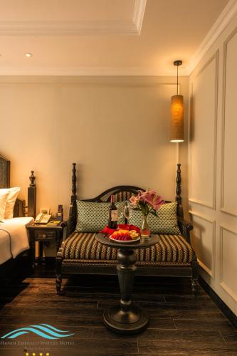 a room with a couch and a table with flowers on it at Hanoi Emerald Waters Hotel Valley in Hanoi