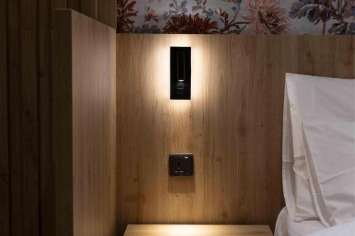 a light on a wooden wall next to a bed at University Boutique Rooms in Msida