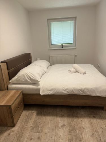 a bedroom with a bed with white sheets and a window at Apartmán Komenského 14 in Prievidza