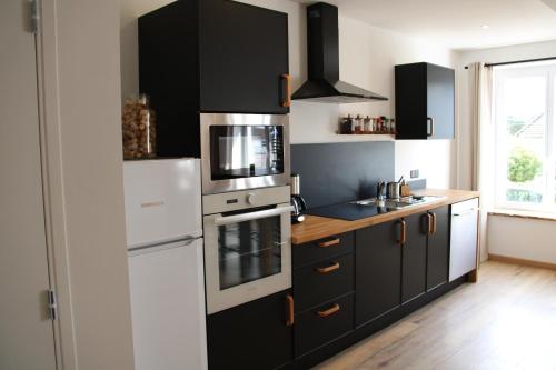 a kitchen with black cabinets and a white refrigerator at Appart Centre Village in Condette