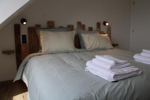 a bed with towels stacked on top of it at Appart Centre Village in Condette