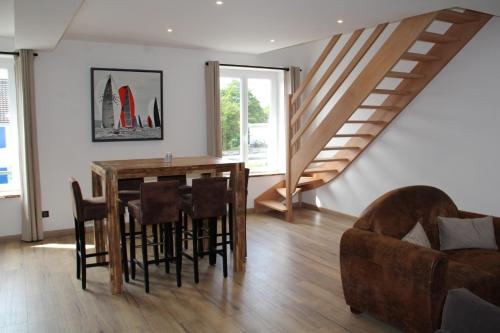 a dining room with a table and chairs and a staircase at Appart Centre Village in Condette