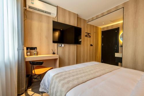 a hotel room with a bed and a flat screen tv at 一间森林酒店交通大学延安西路地铁站店 in Shanghai