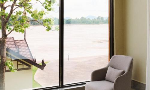 a chair sitting in front of a window with a view at MonMonBoutique Hotel in Thakho
