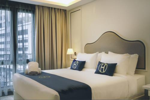 a hotel room with a large bed with blue and white pillows at The Host Hotel in Ipoh